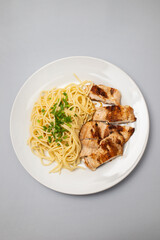boiled spgaghetti with grilled chicken breast on plate