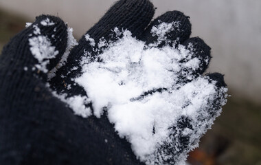 Snow in a black glove. Person holding snow in a black glove close-up