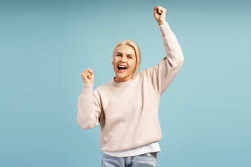 Excited woman celebrating with raised arms on blue background