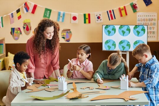Multiethnic group of children cutting cardboard during art and craft class making dinosaur figures and learning about Earth history copy space