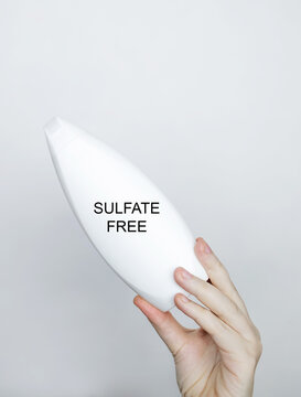 Female hands holding a can of shampoo, where it is written sulfate free, no sulfates. The concept of safe composition of shampoo without aggressive components