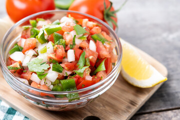 Traditional Mexican Pico de Gallo sauce in bowl on wooden table