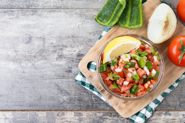 Traditional Mexican Pico de Gallo sauce in bowl on wooden table. Top view. Copy space