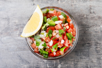 Traditional Mexican Pico de Gallo sauce in bowl on wooden table. Top view