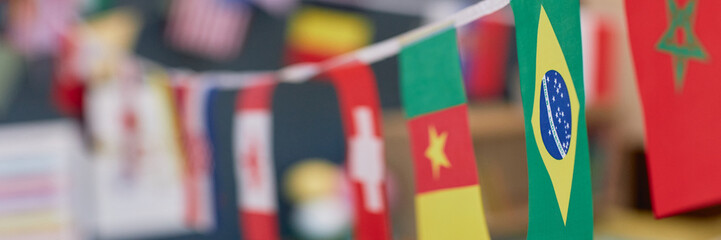 Header image close up background image of various country flags decorating school classroom or kindergarten room copy space