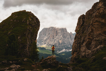Randonneur sur un rocher entre deux formations rocheuses avec montagnes majestueuses en...
