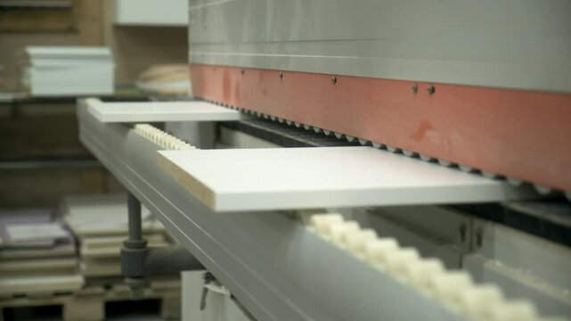 automated woodworking process, worker puts chipboard detail in edge banding machine, closeup