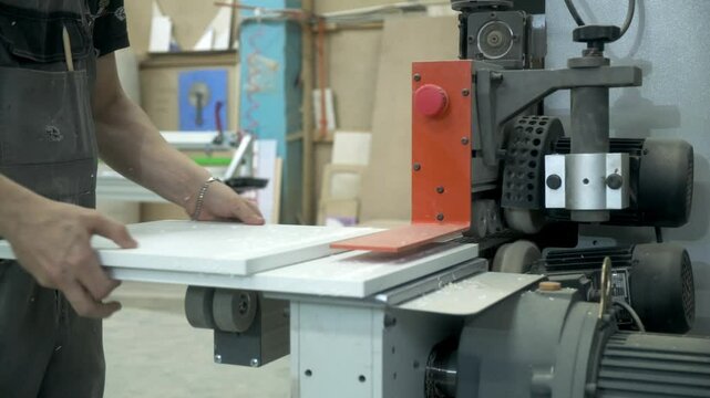 automated woodworking process, worker puts chipboard detail in edge banding machine, closeup