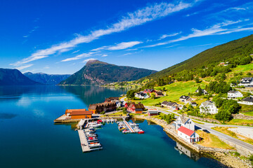 Obraz premium Majestic view of Norwegian fjord with serene waters and charming village under bright blue sky