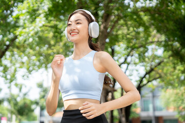 Happy slim beautiful woman wearing sportswear jogging in the park with sunrise. Young beautiful...