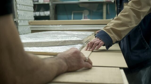 Close-up of furniture packers taking measurements for packing goods. Production and packaging concept.