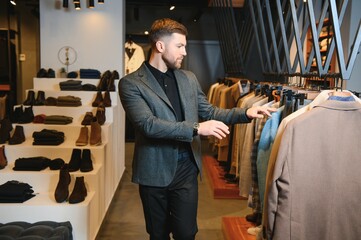 Modern young handsome businessman, looking and choosing classical suit in the suit shop
