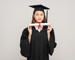 Happy asian woman in graduation costume with cap holding diploma on isolated background. College...