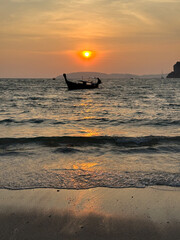 A beautiful boat is gently floating in the vast ocean during sunset