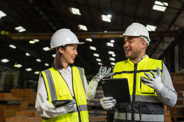Professional engineer and technician wearing safety helmet analyzing meeting with tablet in factory warehouse. Confident factory workers group inspection industry factory. Teamwork concept.