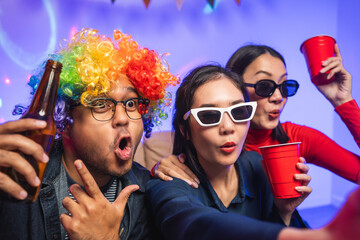 Fototapeta premium New Year's Party. Group of asian friend party in the house with disco light having fun and dancing together. Enjoy Singing karaoke listening music drinking beer celebration in new year happy hour.