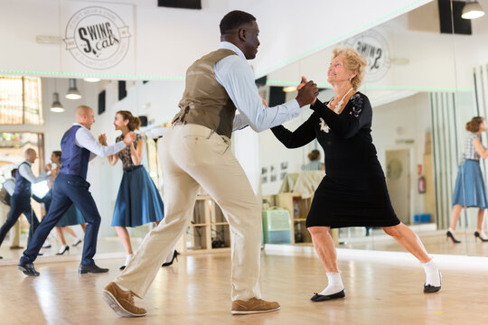 Woman pensioner with african man practising charleston