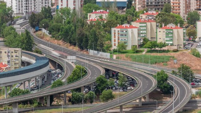 Aerial top view of highway multilevel junction road in urban populated area timelapse. Intersection and overpass with metro train line. Odivelas district in Lisbon, Portugal