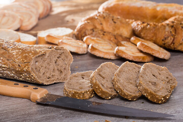 Slices of wheaten bread and knife on wooden surface