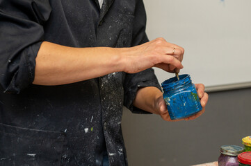 Male artist mixing blue paint in studio setting