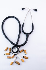 High-angle shot of stethoscope with cigarette butts - stop smoking concept.