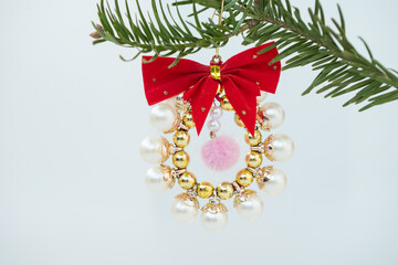 Festive pearl and gold christmas wreath ornament on pine branch