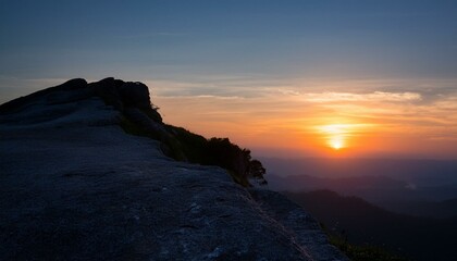 높은 절벽 위에 반짝이는 새벽녘의 태양, 어두운 하늘이 점차 물드는 장면