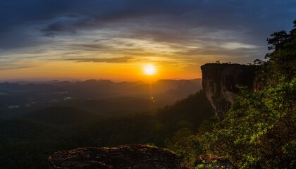 높은 절벽 위에 반짝이는 새벽녘의 태양, 어두운 하늘이 점차 물드는 장면