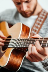 Fototapeta premium Young man playing acoustic guitar in casual attire, focused on music creation in a cozy indoor setting