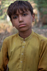 Candid Portrait of a Young Boy in Yellow Traditional Clothing with a Thoughtful Expression Outdoors
