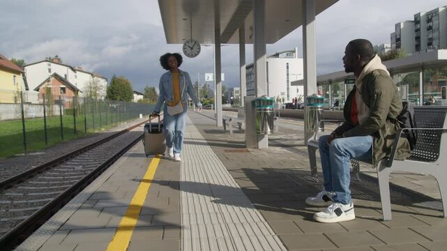 Happy young African American couple hugging at a train station, meeting after a long journey, wide shot. Travel, welcome, and love concepts.