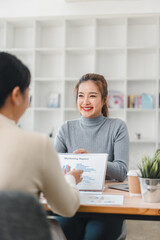 Two women discussing marketing report in modern office