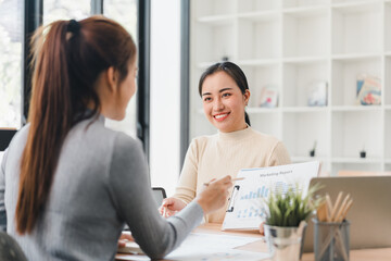 Fototapeta premium Two women discussing marketing report in modern office