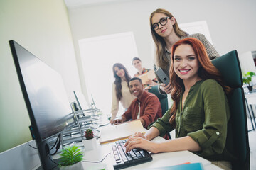 Photo of smiling happy web designers working startup together typing modern gadget indoors workplace workstation