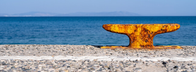 Rostiger Poller am Hafen am Meer mit Insel im Hintergrund