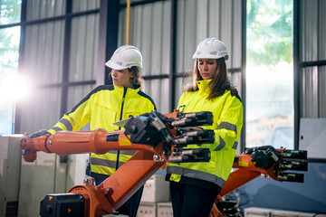 Two Workers Operating a Robotic Arm in a Factory Setting During Daylight