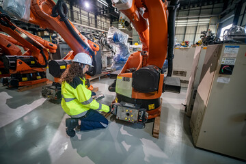 Fototapeta premium Technician Inspecting Robotic Arm in Modern Industrial Facility
