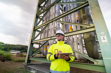 Worker in Safety Gear Inspects Gas Storage Facility While Using a Tablet for Monitoring Operations