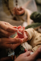 Anointing. Unction at baptism. Baby leg. The priest performs chrism at baptism. Temple, Orthodoxy. Closeup of tiny baby feet, sacrament of baptism ceremony.
