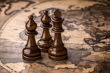 Three wooden chess pieces king and bishops strategically placed on an antique world map, symbolizing strategy, leadership, global influence, planning, and decision-making