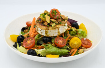 Ensalada con queso de cabra, aceitunas y tomates sobre fondo blanco