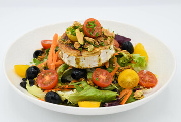 Ensalada con queso de cabra, aceitunas y tomates sobre fondo blanco