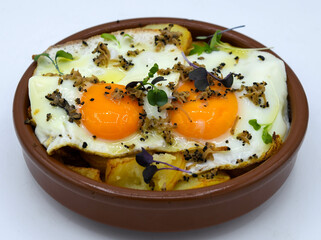 Huevos fritos con patatas sobre fondo blanco