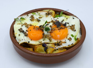 Huevos fritos con patatas sobre fondo blanco