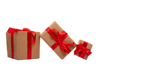 Three gift boxes of different sizes, wrapped in brown paper and decorated with red satin ribbons, arranged on an impeccable isolated background. Perfect for celebrations.