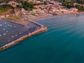 Aerial view of coastal town with beach, pier, and boats at dusk.