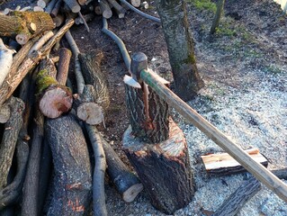 Obraz premium The process of chopping firewood with a large cleaver. An axe is stuck in a wooden log outside.