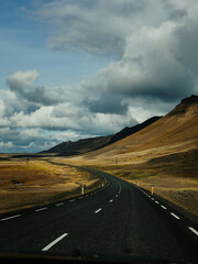 Long winding road through Icelandic highlands beneath dramatic clouds