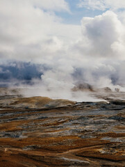 Steaming geothermal landscape under dramatic cloudy skies in Iceland