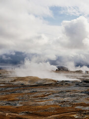 Steaming geothermal landscape under dramatic cloudy skies in Iceland
